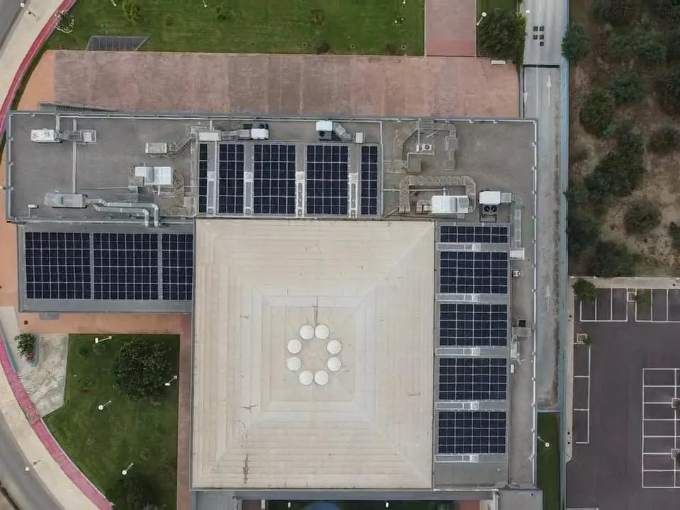 Vista cenital de un edificio público con módulos fotovoltaicos en sus cubiertas