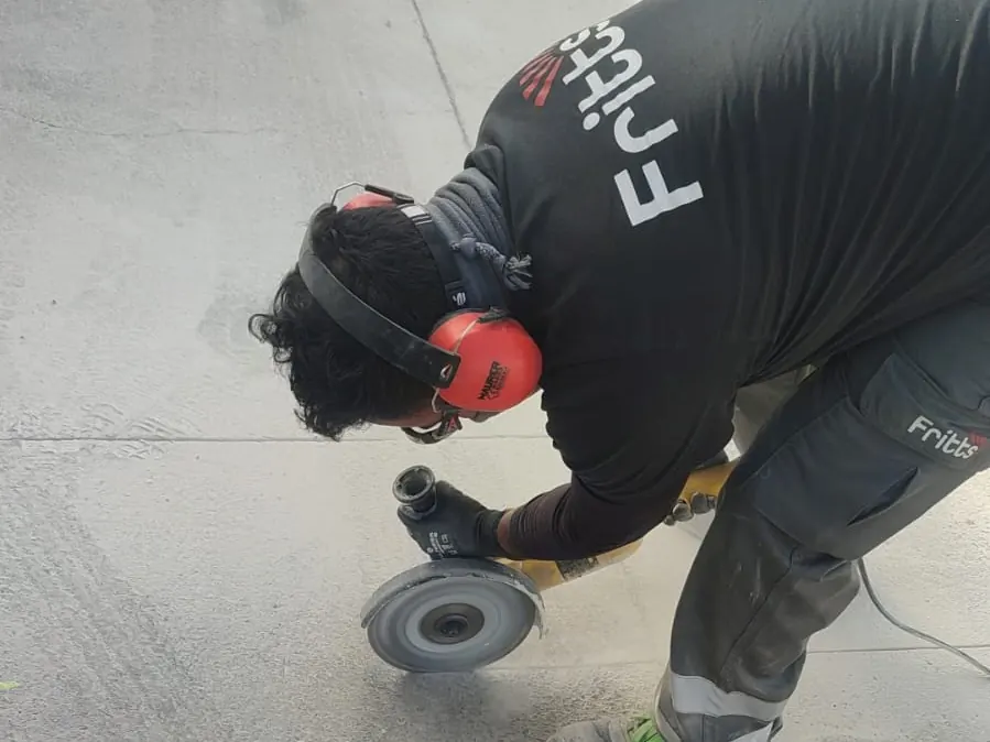 Operario de Fritts cortando pavimento de hormigón con radial