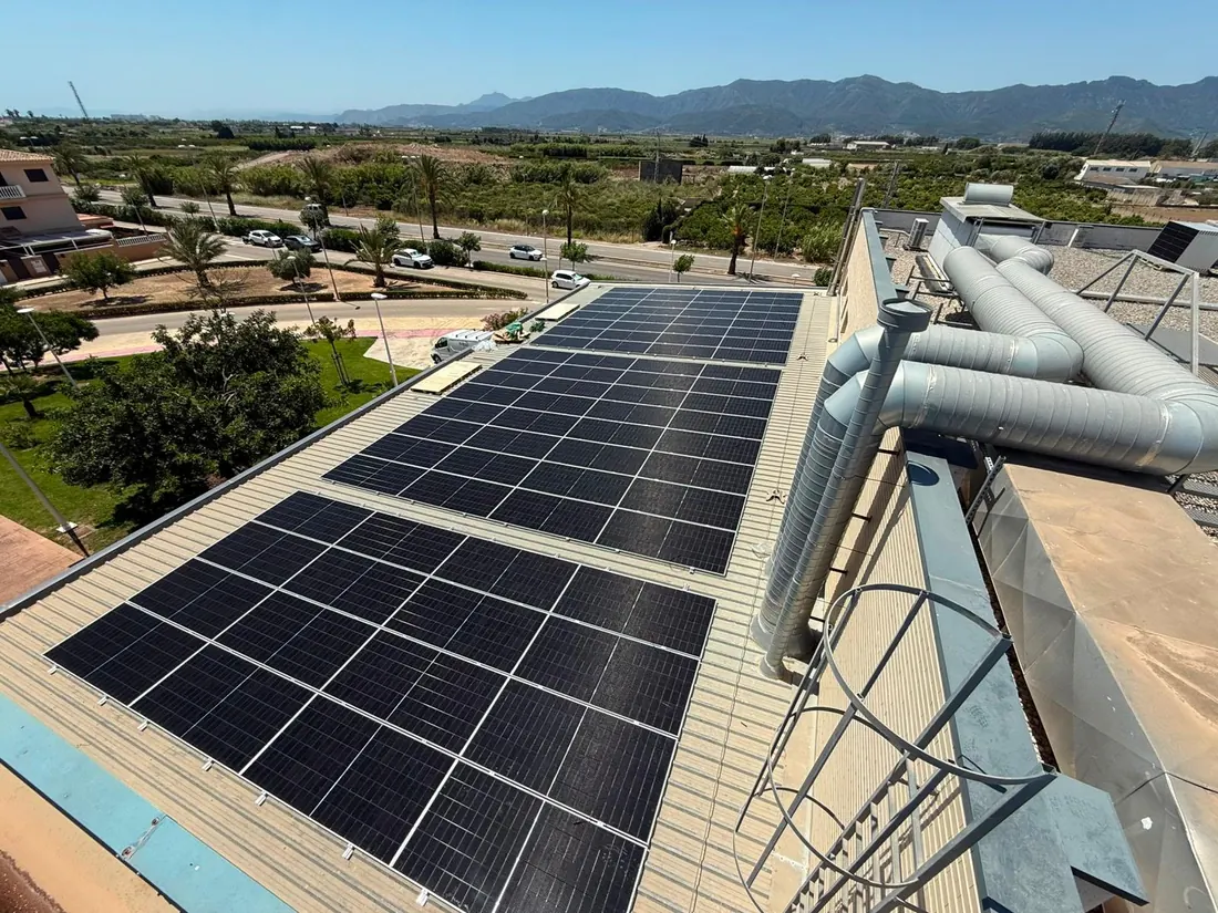 Módulos fotovoltaicos sobre la cubierta de un edificio con la sierra al fondo