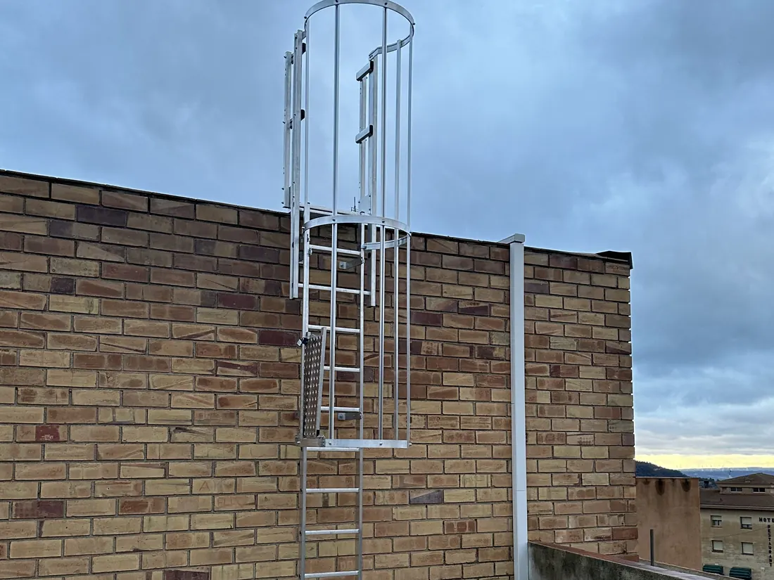 Escalera fija con jaula de protección en el muro de una azotea