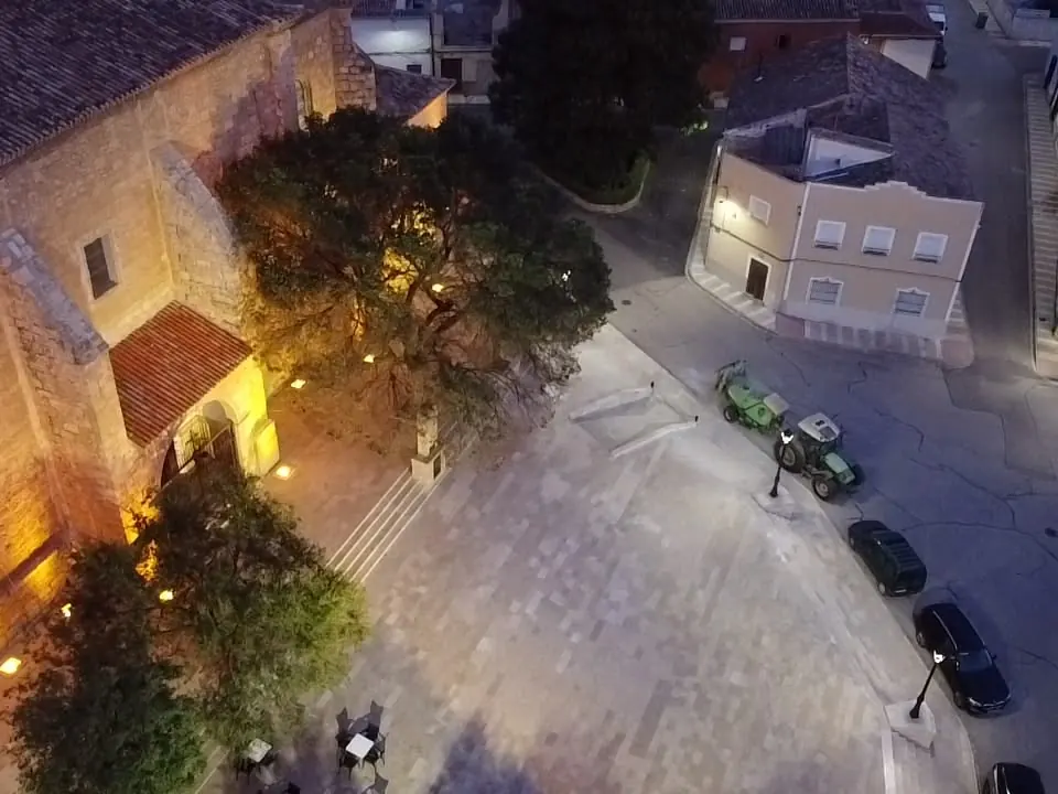 Plaza peatonal iluminada de noche junto a una iglesia