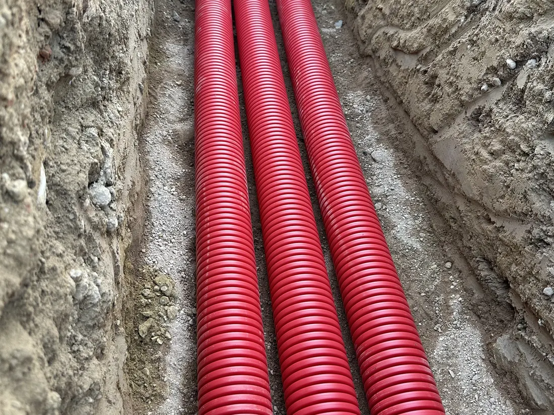 Tubos corrugados rojos tendidos en el fondo de una zanja
